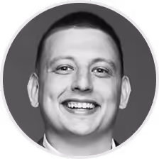 Black and white portrait of a smiling man with short hair in a circular frame.