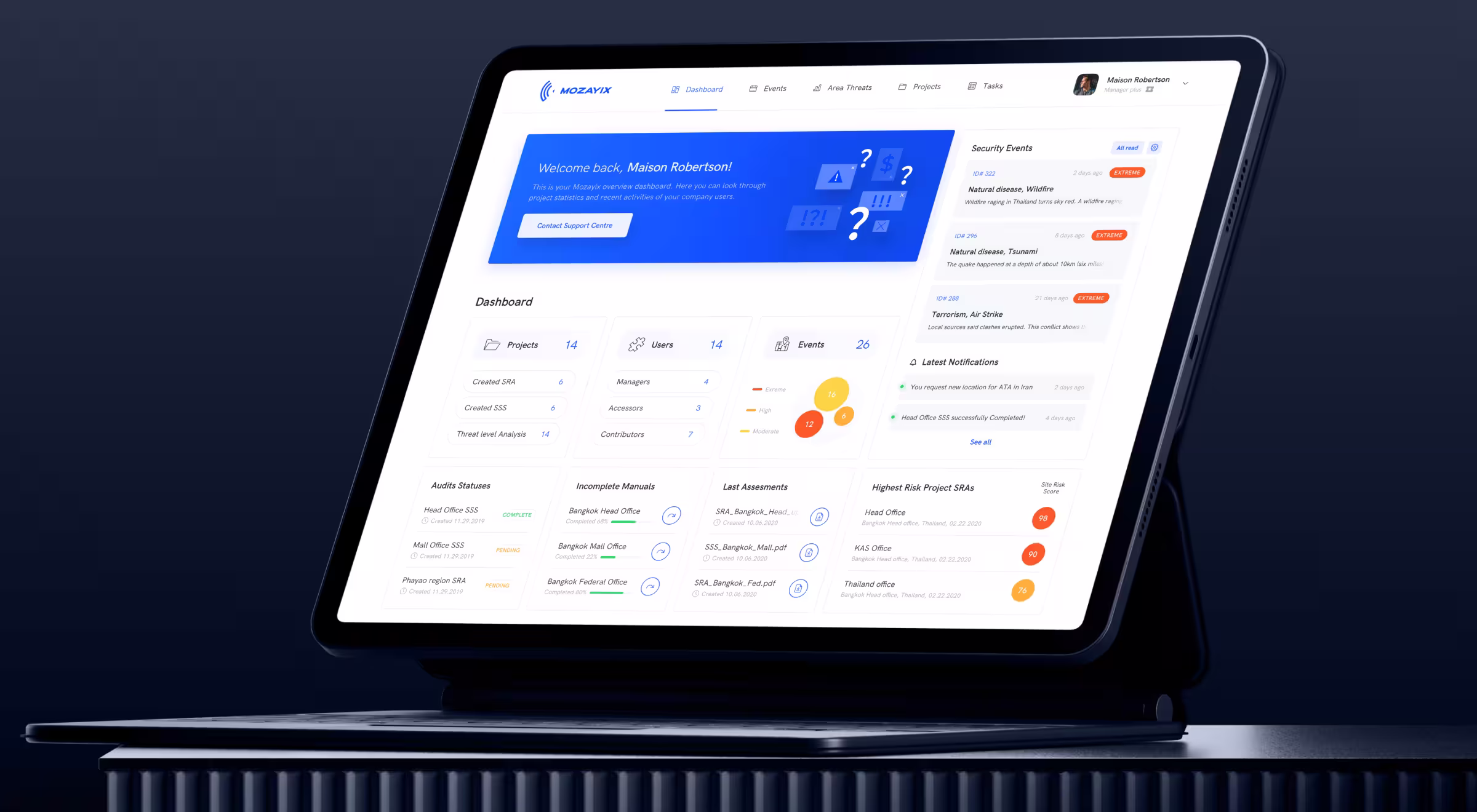 Laptop displaying an enterprise security and risk management dashboard with project status metrics, threat monitoring, audit progress tracking, risk scoring, and real-time notifications, presented in a clean, data-driven interface against a dark blue background.