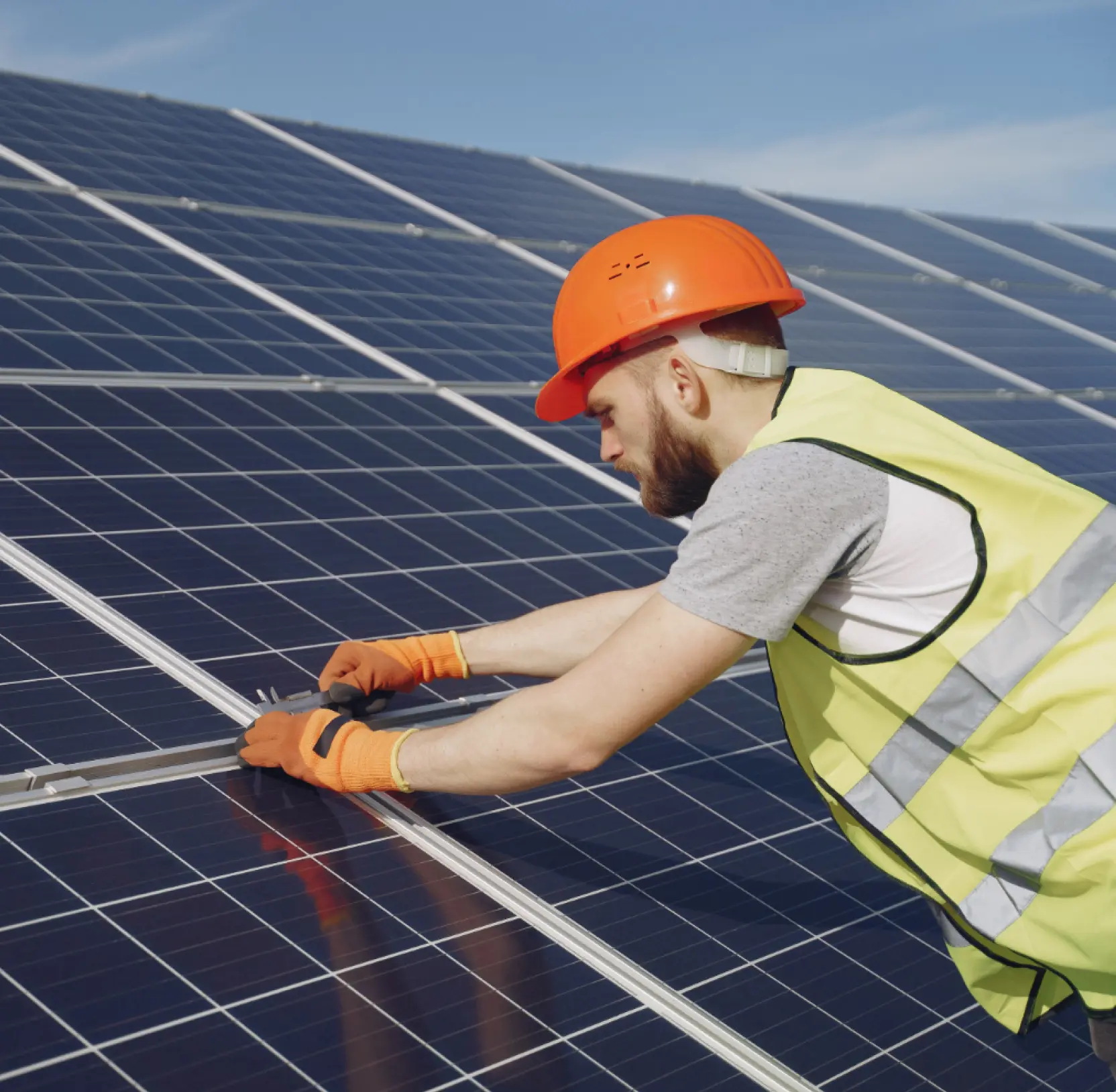 Installer in a hard hat and hi-vis vest fitting a solar panel