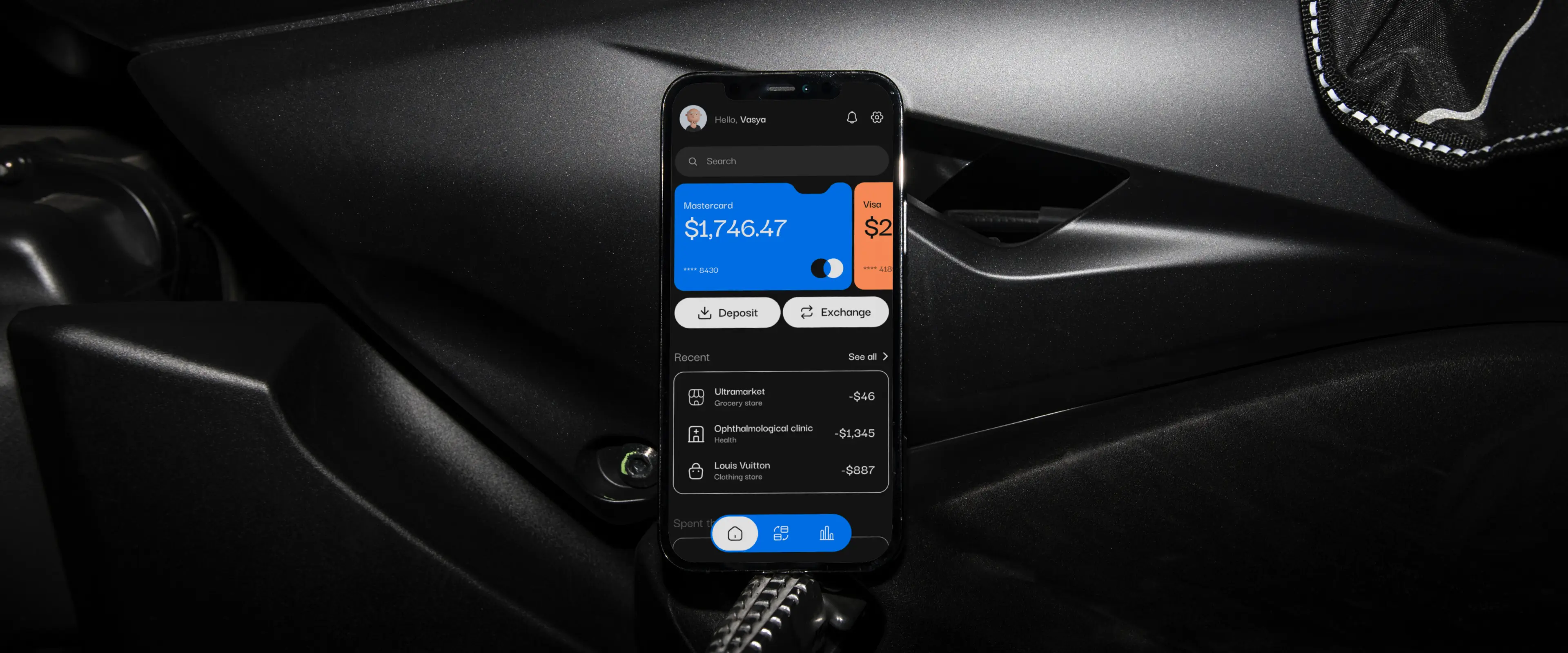 Finance app with balance and transactions on a phone in a car.