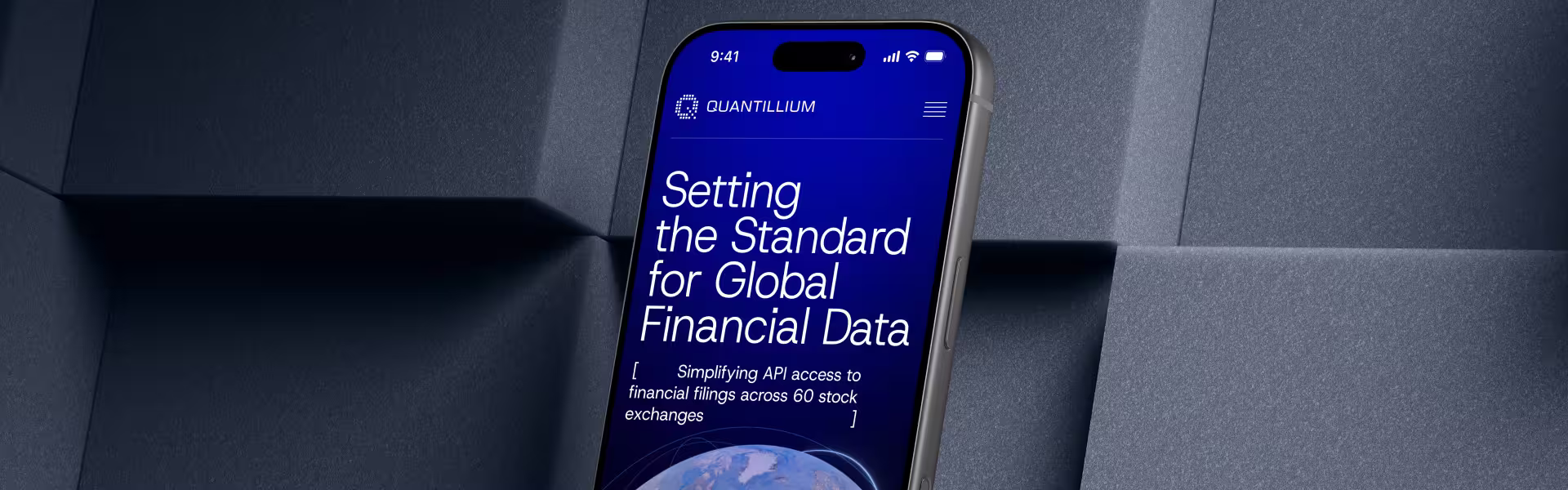 Smartphone mockup tilted against a textured gray background, displaying the Quantillium website.