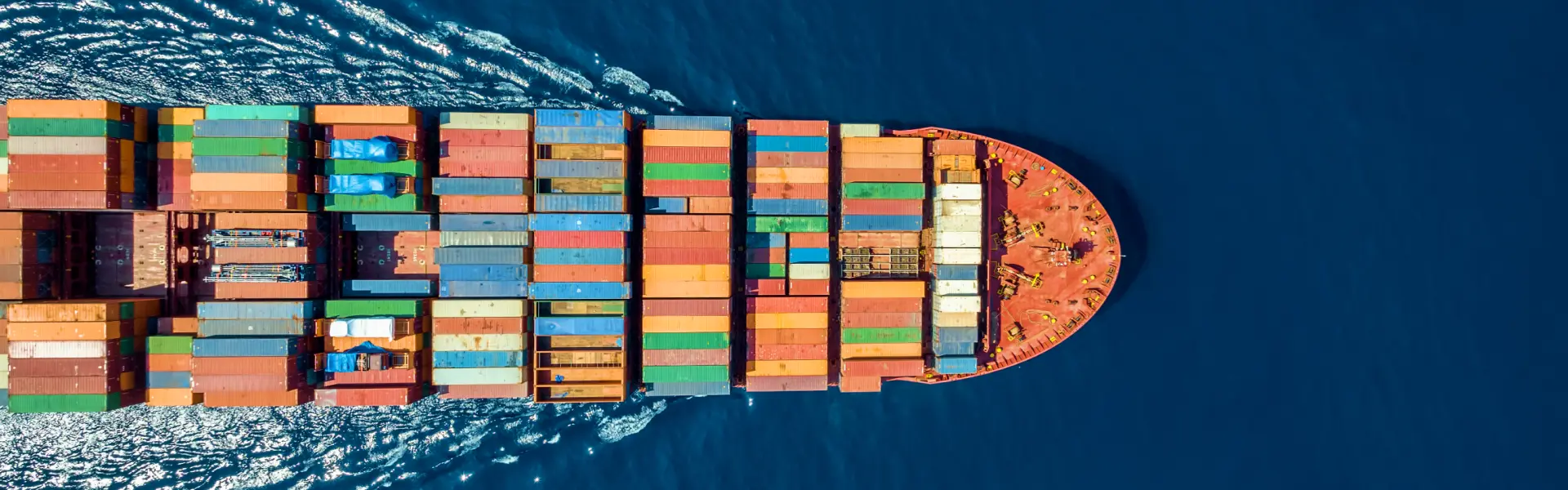 Aerial view of a container ship loaded with stacked cargo containers crossing open blue water
