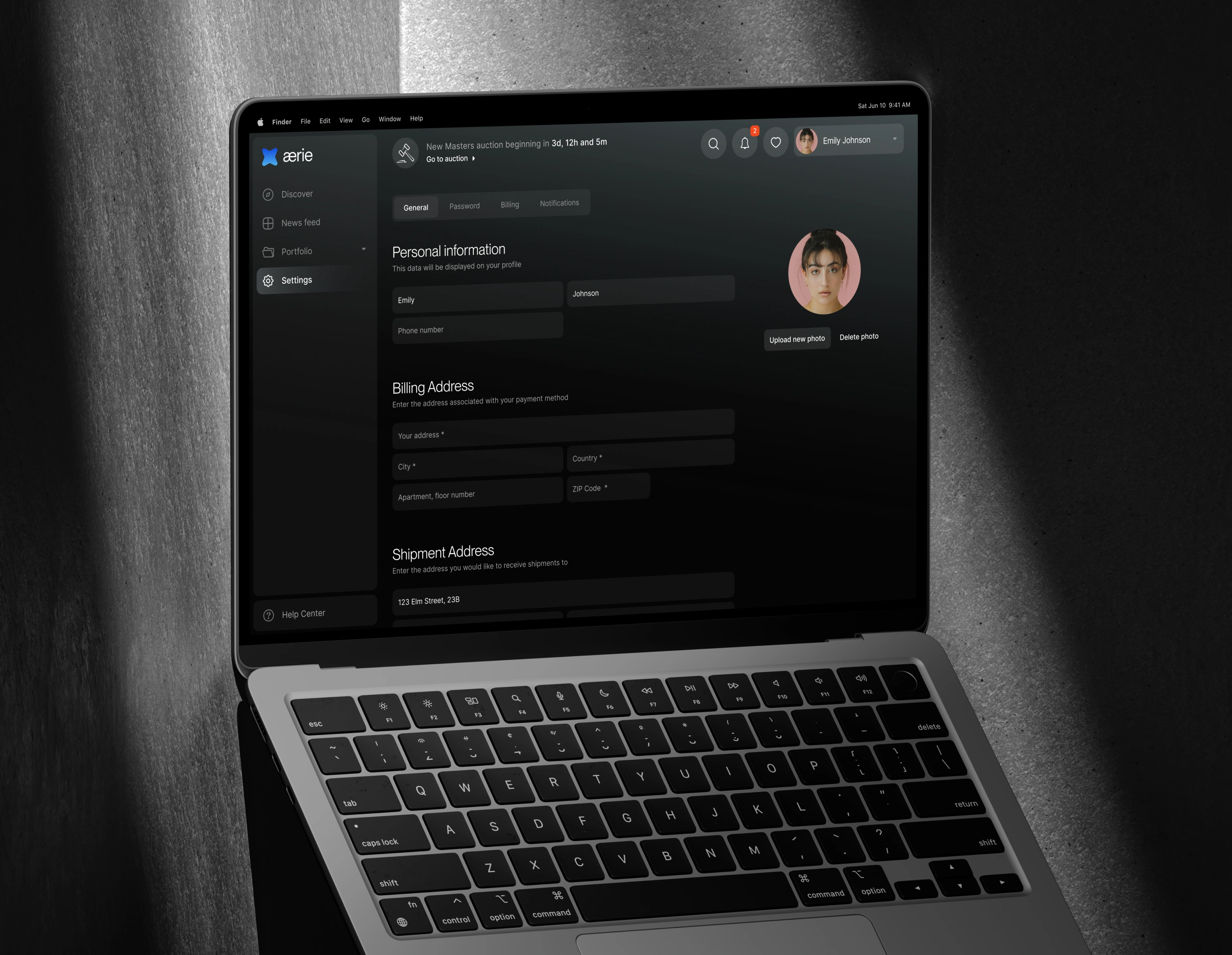 MacBook against a lit concrete wall showing Aerie's Settings page with personal and billing fields.